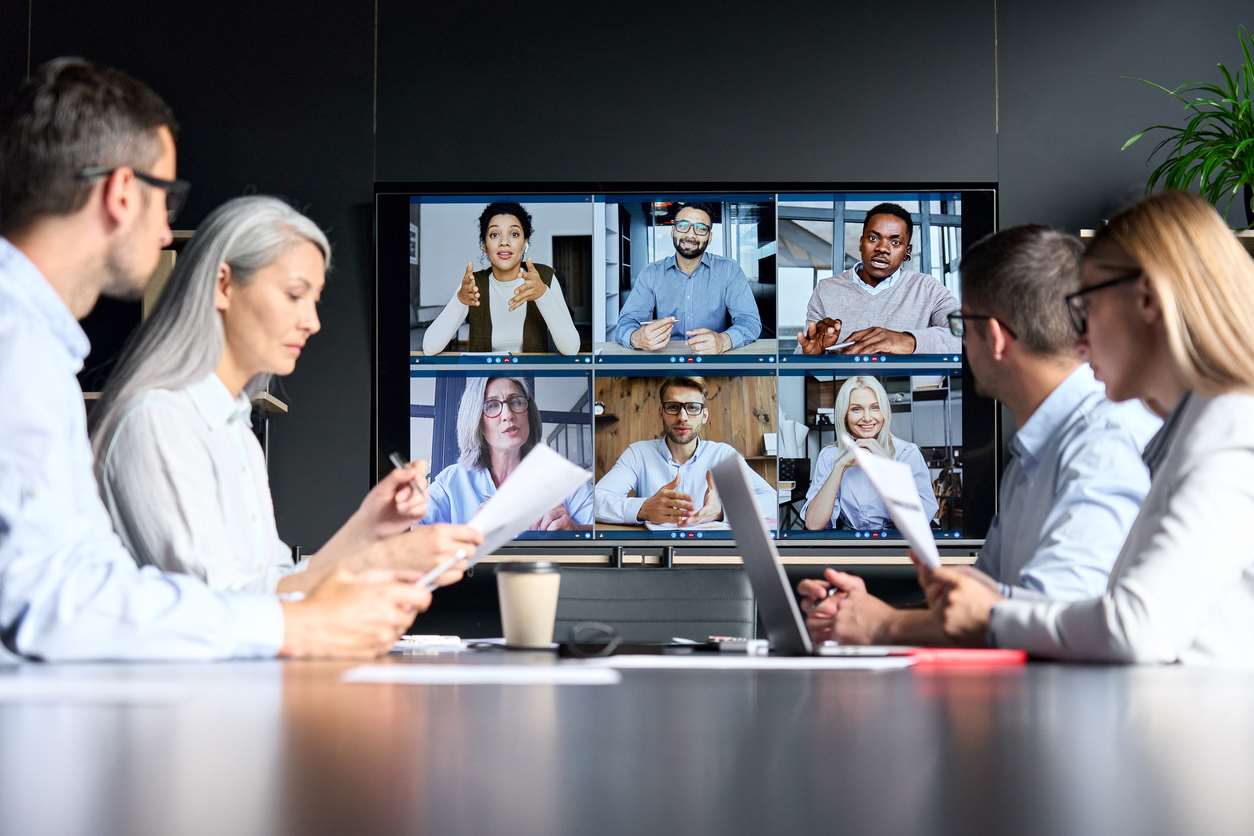JMA online videoconference in meeting room with diverse people sitting in modern office and multicultural multiethnic colleagues on big screen monitor. Business technologies concept.